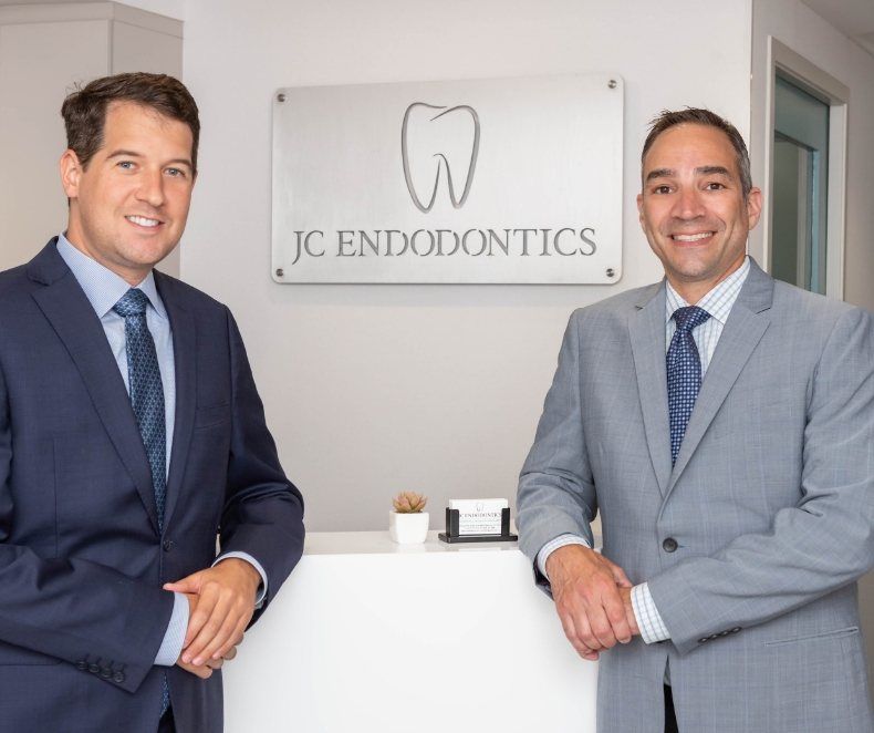 Smiling endodontists by front desk at J C Endodontics Root Canal Specialists
