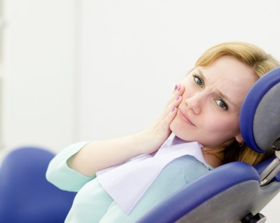 Dental patient holding the side of her jaw in pain