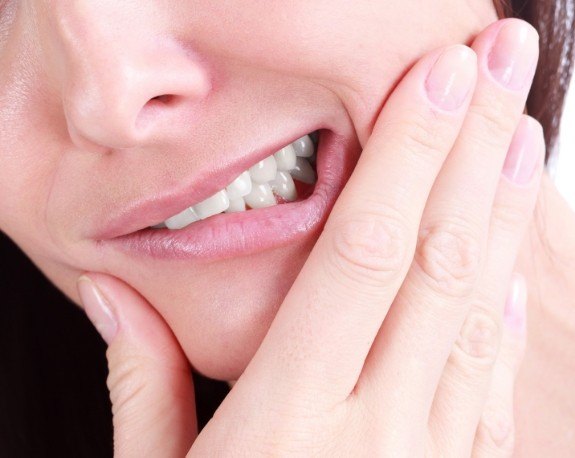 Close up of person holding their cheek in pain before endodontic retreatment