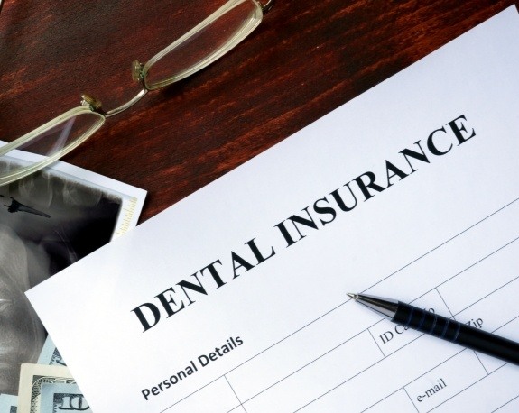 Dental insurance paperwork on dark wood table