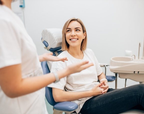 Young woman in dental chair smiling at her dentist