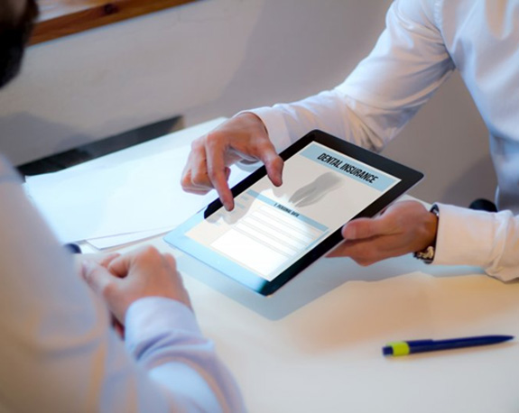 Dentist reviewing a patient’s dental insurance with them using a tablet 